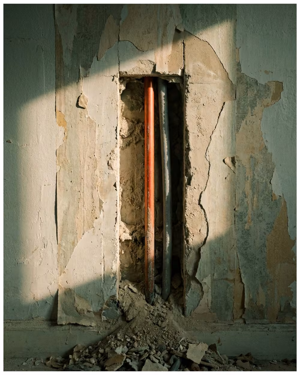 Saignée ouverte dans un mur de plâtre ancien, gaine et tube de cuivre posés
